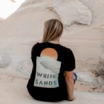 Female sitting against a rock with a white sands national park t-shirt