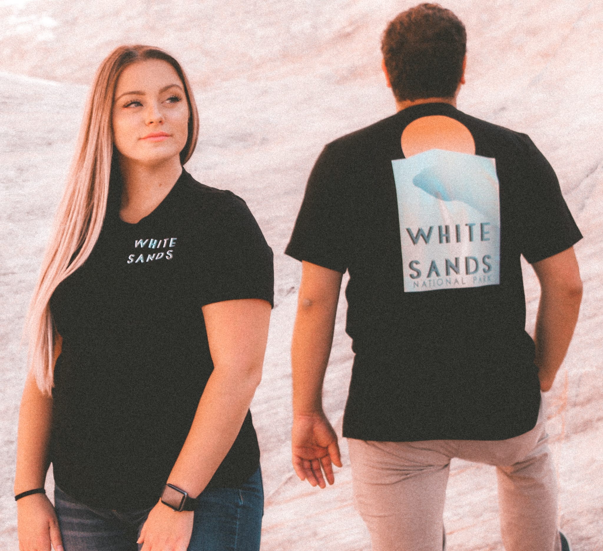 Male and female walking on a large rock with white sands national park t-shirts