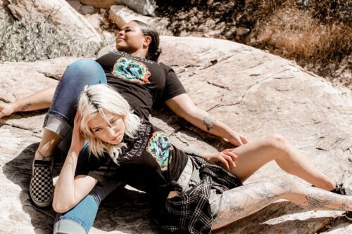 two females laying next to eachother in the mountains with a black yellowstone national park shirt