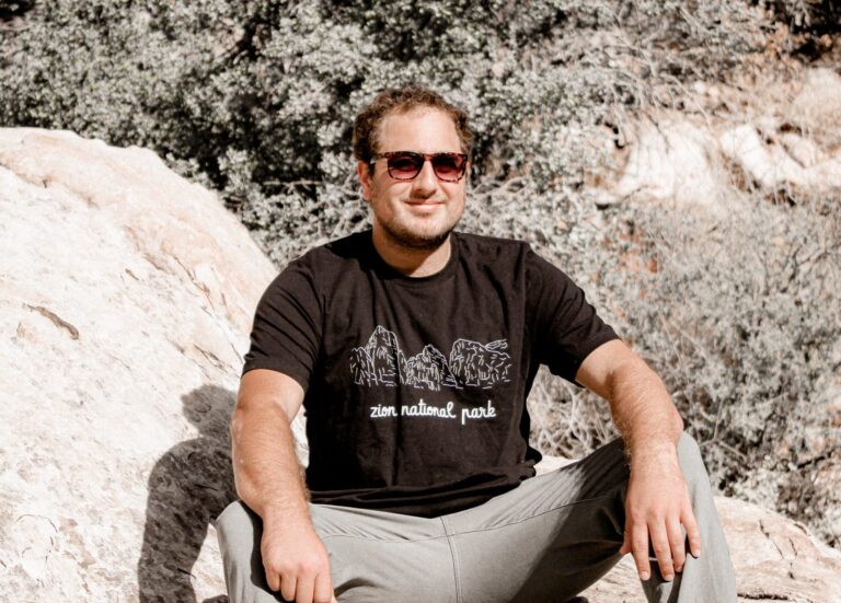 Male sitting on rock with zion national park black t-shirt