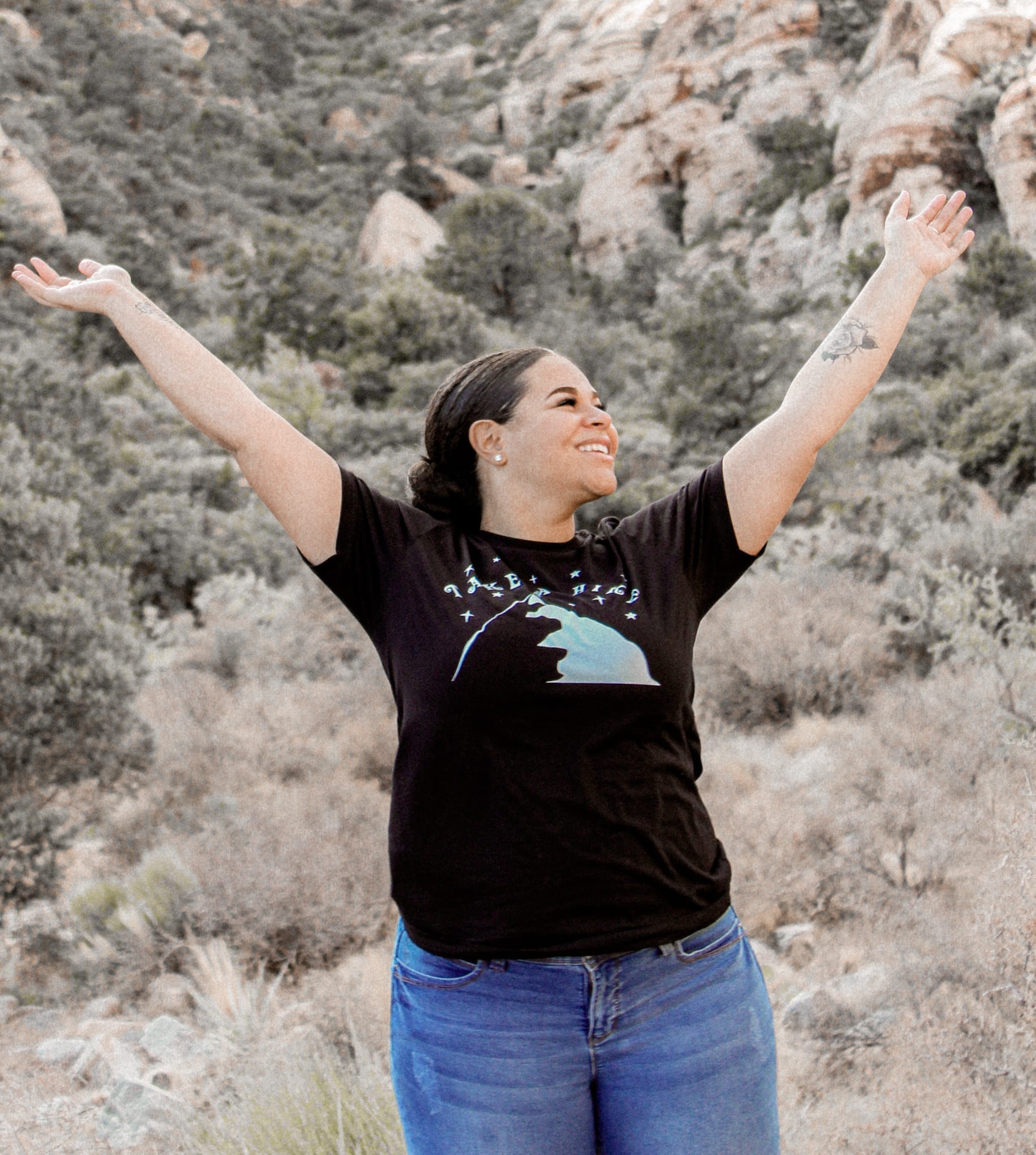 female with a black take a hike shirt with green hills behind her