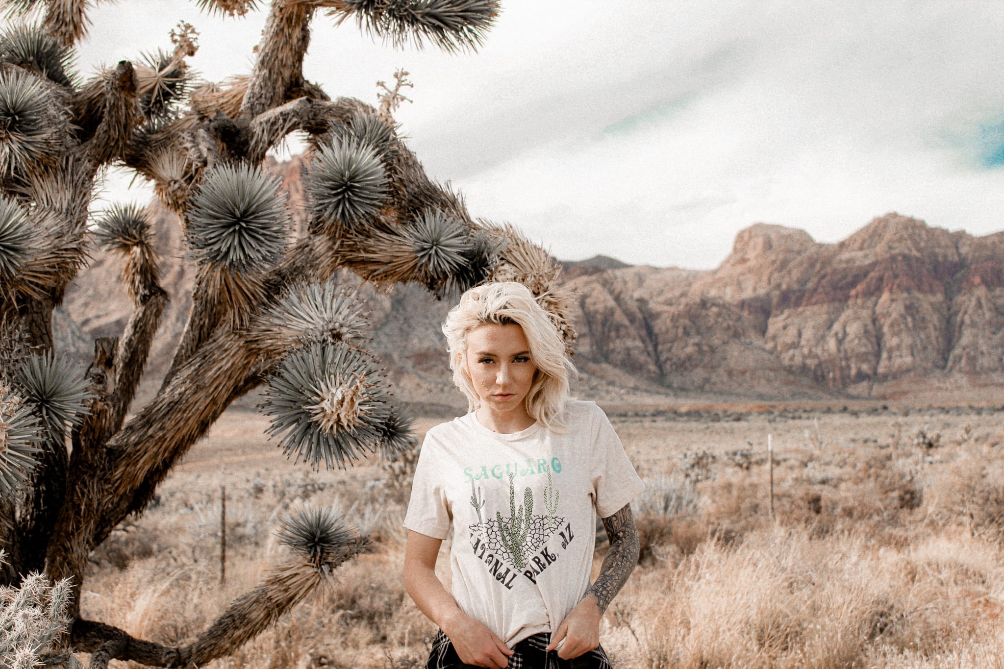 woman standing next to a joshua tree in a cream colored saguaro national park t-shirt